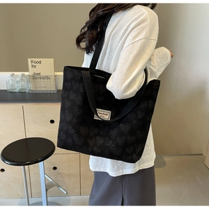 Close-up of black canvas tote bag with heart pattern and wide shoulder straps
