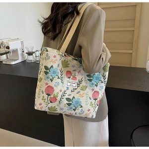 Detailed side view of a large canvas tote bag featuring vintage floral embroidery and wide strap