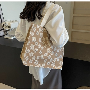 Detail of khaki tote bag featuring white 3D floral embroidery and canvas texture