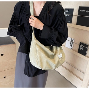 Détail du sac croissant vert clair avec texture plissée et un papillon 3D blanc
