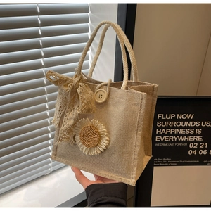 Détail d'un sac en lin avec marguerite tissée, nœud en dentelle et anse en chanvre