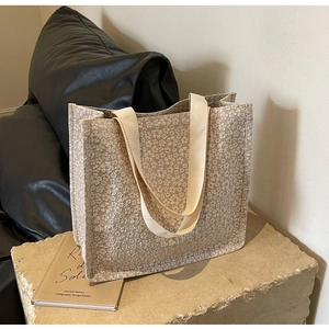 Gros plan sur le sac cabas en toile jacquard beige avec motifs floraux et anses crème