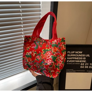 Détail du sac fourre-tout rouge à fleurs en toile avec anses tressées et bouton doré
