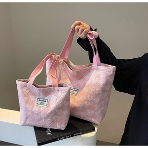 Detail view of large and small pink canvas tote bags with white embossed hearts