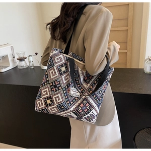 Détail du sac cabas tissé aux motifs géométriques avec une bandoulière noire et étiquette