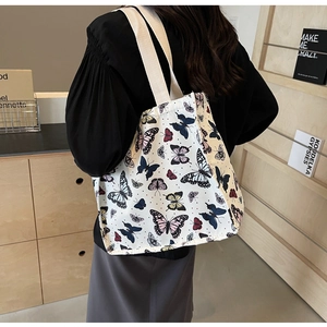 Detail of canvas tote bag with butterfly prints shown on person's shoulder from behind