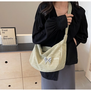 Détail du sac en nylon vert sauge avec pendentif papillon argenté dans un décor moderne