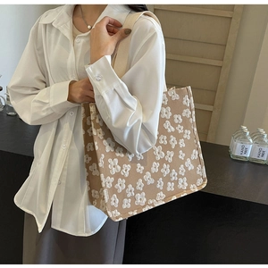 Detail of khaki canvas tote bag featuring 3D white flower embroidery and wide shoulder strap