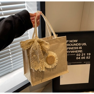 Detail of jute tote bag showing lace bow, daisy applique, and woven rope handles