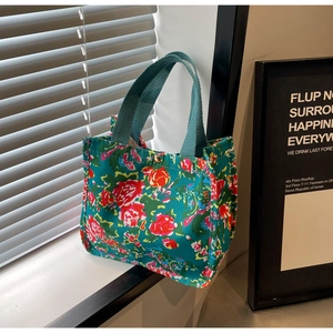 Détail du sac cabas en toile fleurie avec poignées tressées vertes et boucle dorée