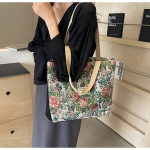 Detail of vintage floral canvas tote bag with thick beige straps and woven logo patch