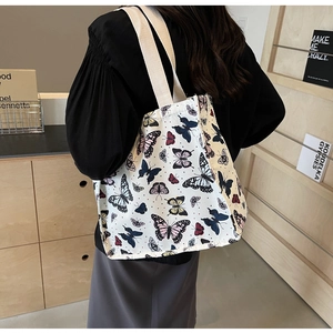 Detail of a large canvas tote bag with colorful butterfly prints shown on a shoulder