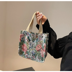 Detailed view of floral jacquard tote bag featuring vibrant red rose patterns and woven handles