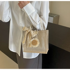 Close-up of linen lunch bag with lace bow, sunflower decor and wooden button closure