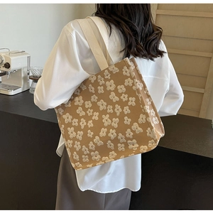 Detail of khaki canvas tote bag featuring white 3D floral textures and fabric shoulder strap