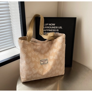 Detail of beige jacquard tote bag featuring 3D heart patterns and woven fabric texture