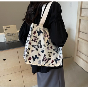Detail of white canvas tote bag featuring vibrant butterfly prints and sturdy woven straps