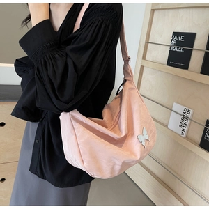 Détail du sac hobo en nylon rose avec un ornement élégant en forme de papillon argenté