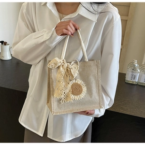 Detail of beige cotton linen handbag featuring lace bow and sunflower floral decor