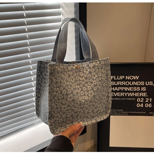 Close-up of blue floral tote with 3D embroidery, light blue straps, and gold magnetic buckle