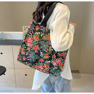 Vue portée du grand sac cabas en toile avec motif floral et anses noires épaisses