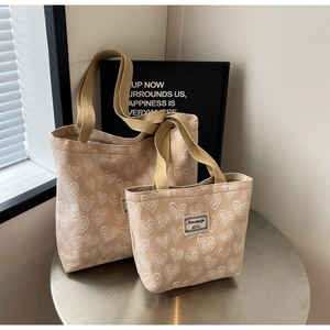 Detail of premium beige tote bags featuring embossed heart patterns and canvas straps