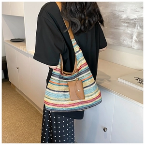 Detail of colorful striped woven tote bag with brown leather handles and coin purse charm