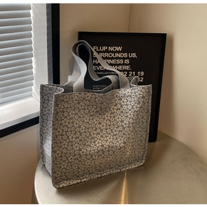 Détail du sac cabas en brocart floral argenté avec des poignées tissées grises