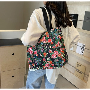 Gros plan d'un sac cabas en toile noire avec broderie florale rouge et bandoulière large