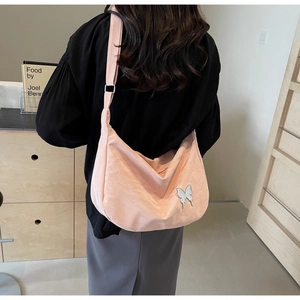 Détail du sac bandoulière rose en forme de croissant avec pendentif papillon argenté