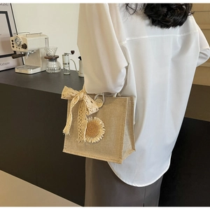 Détail d'un sac en jute beige avec nœud en dentelle et tournesol sur une table de café