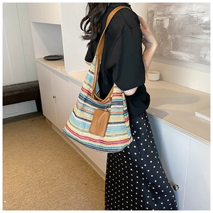 Detailed view of colorful striped woven tote with brown leather straps on model