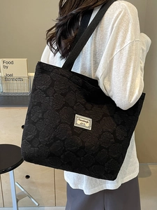 Minimalist black tote bag with rose jacquard pattern and woven shoulder strap on model