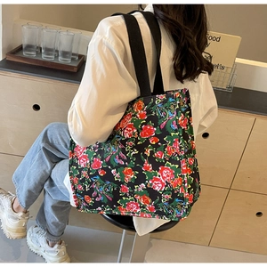 Détail du grand sac cabas en toile à fleurs avec bandoulières noires et motifs ethniques