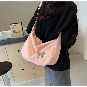 Vue détaillée d'un sac hobo rose avec un papillon argenté sur un tissu plissé doux