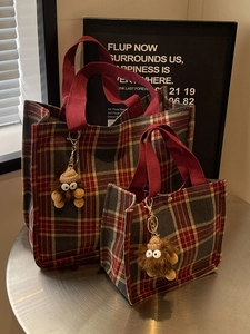 Set of two tartan canvas tote bags with plush monster charms on a metal table