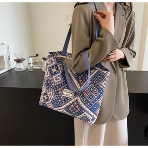 Gros plan sur les motifs jacquard géométriques du sac cabas avec poignée bleue tissée