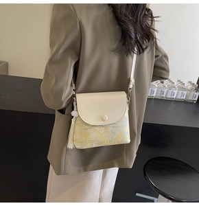 Détail du sac bandoulière crème avec motif jacquard chinois et élégant gland latéral