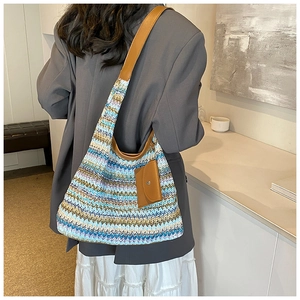 Macro detail of large woven tote bag featuring colorful wave stripes and leather straps