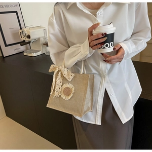 Gros plan du sac en jute beige avec nœud en dentelle blanche et marguerite en 3D