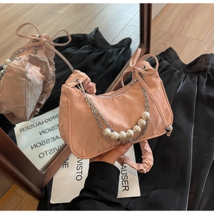 Detail of pink ruched underarm bag with decorative pearl chain and bow handle detail
