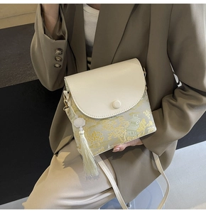 Détail d'un sac bandoulière de style oriental avec rabat en cuir et pompon en soie