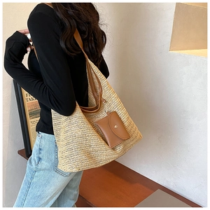 Close-up of woven straw tote bag featuring brown leather shoulder straps and matching coin purse