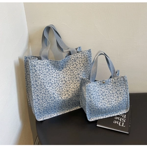 Detail of floral canvas tote bag set in light blue with sturdy woven straps and metal buckle