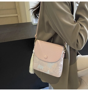 Détail d'un sac bandoulière vintage en jacquard avec motifs et pompon blanc élégant