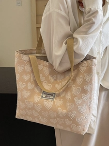 Large beige tote bag with embossed heart texture and chic shoulder straps for daily use