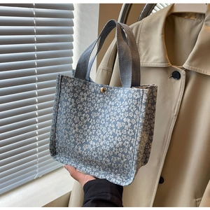 Vue détaillée du sac cabas en tissu jacquard fleuri bleu avec bouton pression doré