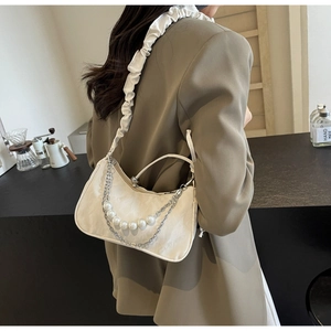 Close-up of beige shoulder bag featuring pearl chain details and ruched strap design