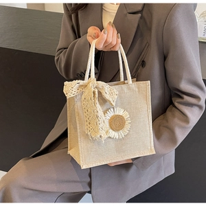 Détail du sac à main en toile beige avec anses en corde et décoration fleur en dentelle
