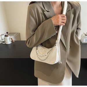 Close-up of pearl and metal chain straps on off-white satin half-moon shoulder bag